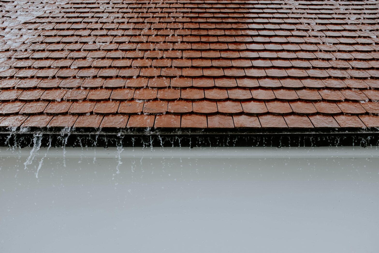 Rainwater overflowing from clogged gutters highlighting the need for rain gutter repair. Signs your gutter needs repair include leaks and water damage.